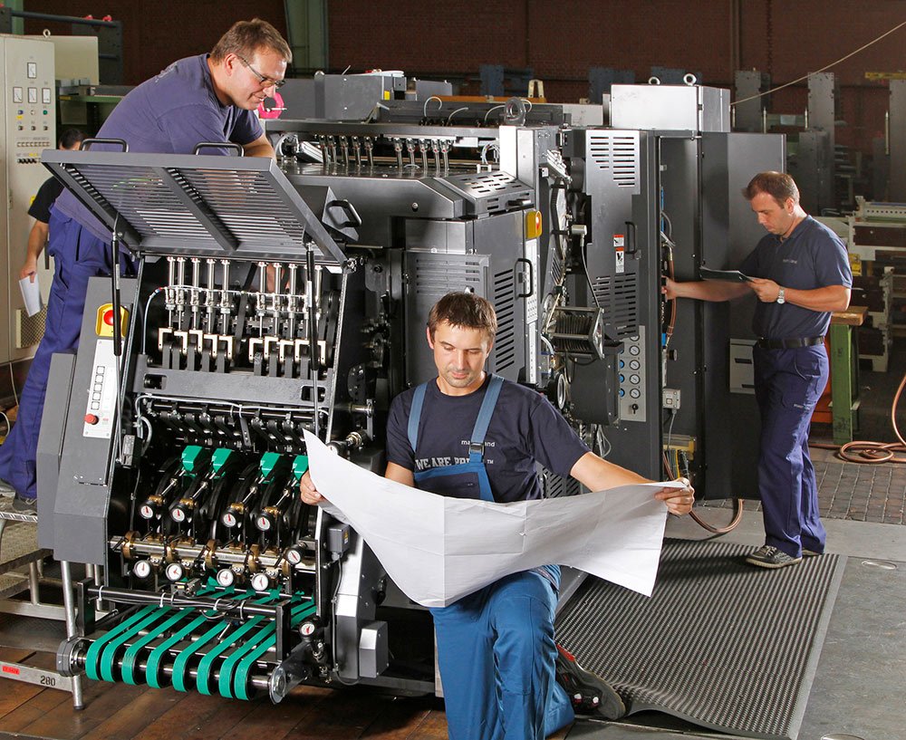 Engineers inspect printing press components during overhaul and renewal work